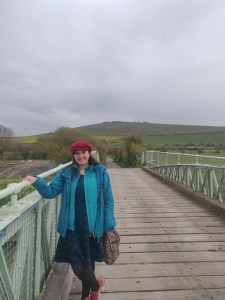 A woman wearing a red cap and blue coat stands on a bridge.